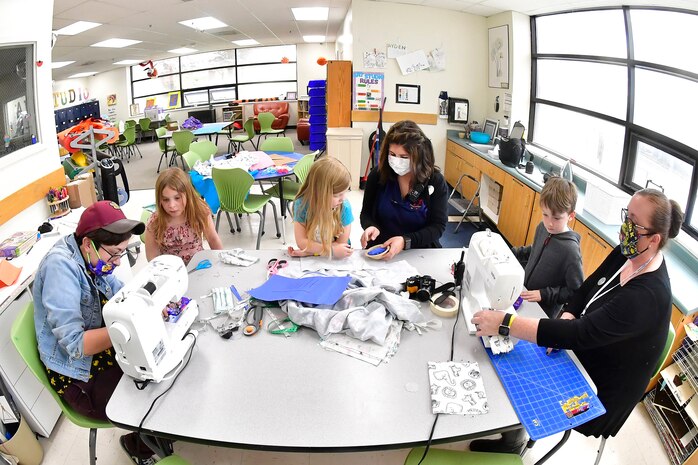 Care giver staff and children crafting face coverings