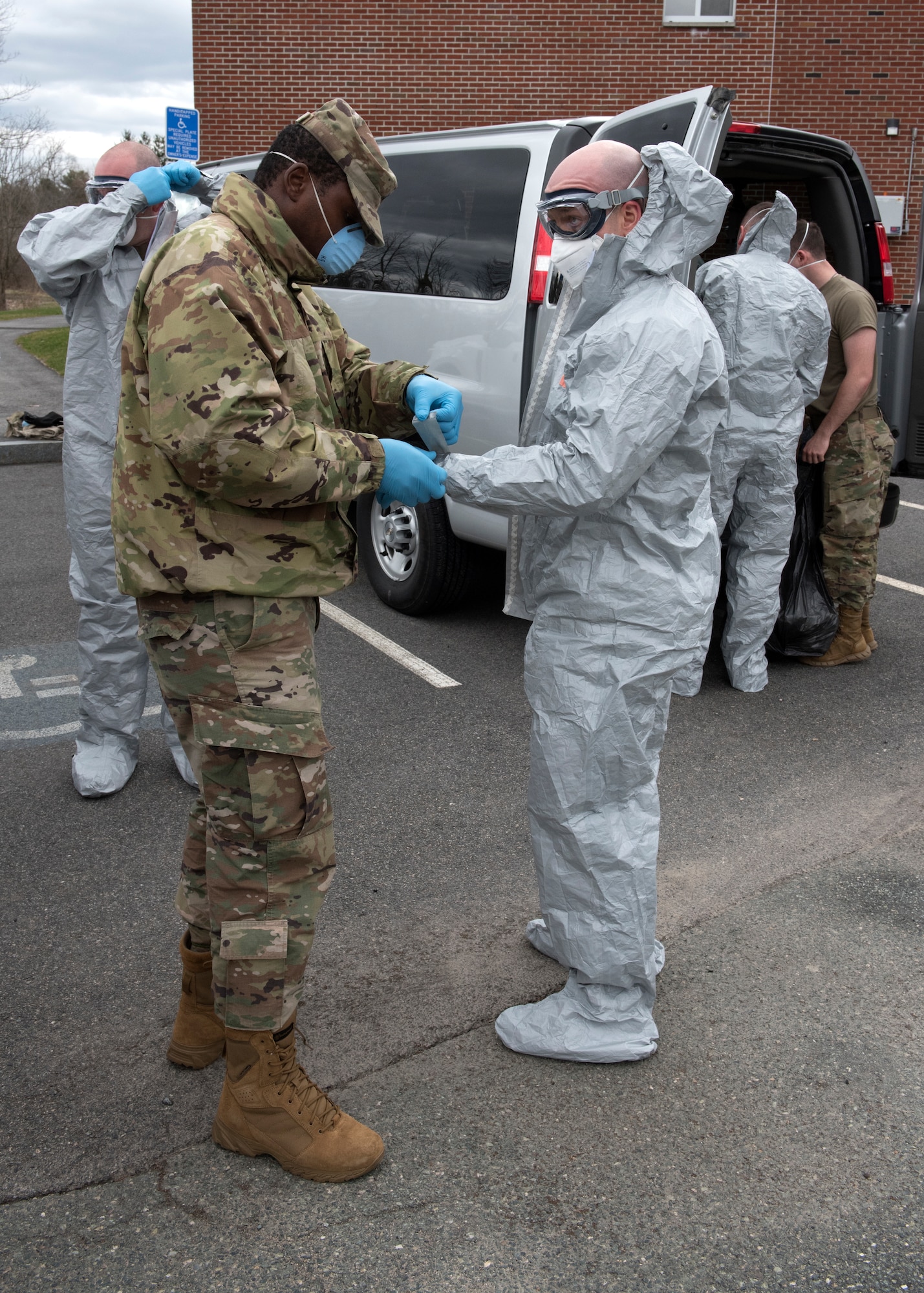 Soldiers and Airmen from the Massachusetts National Guard don proper personal protective equipment (PPE)