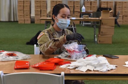 New York Army National Guard Spc. Linda Nquibn, a member of Delta Company, 152nd Brigade Engineer Battalion, puts together a COVID-19 test kit at the Armory at Sage Colleges in Albany, N.Y., April 11, 2020. Thirty New York Army and Air National Guard members are assembling the kits for use at test sites across New York.