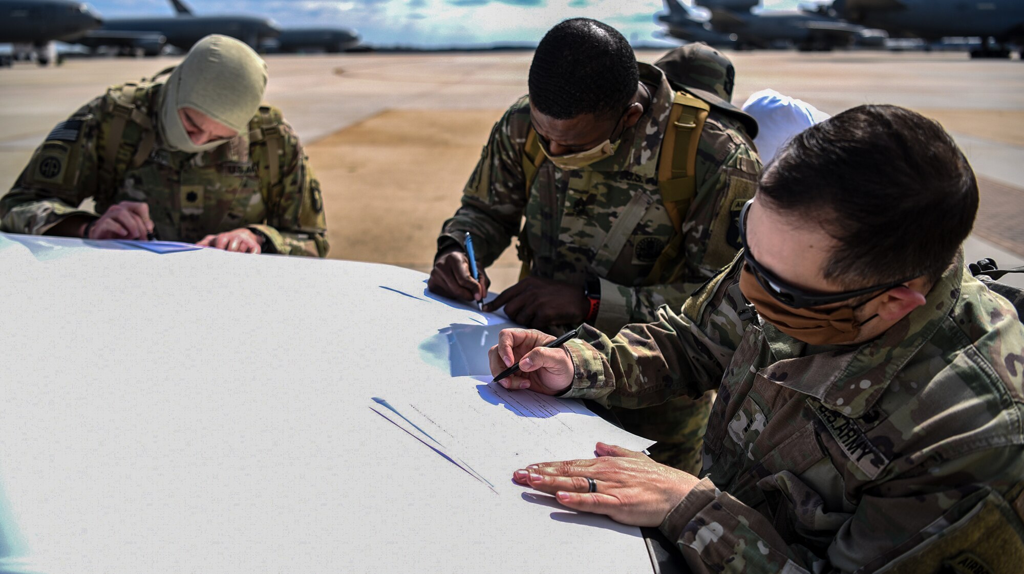 Photo of three servicemembers filling out paperwork.