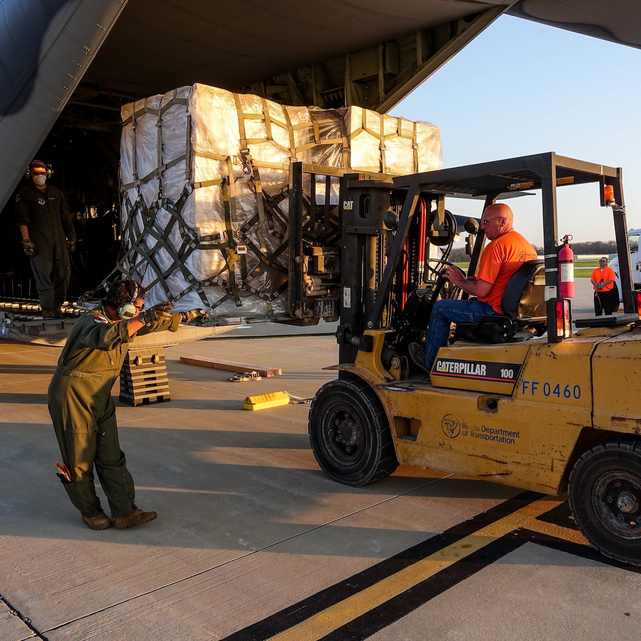 A forklift operator prepares to offload a military cargo plane.