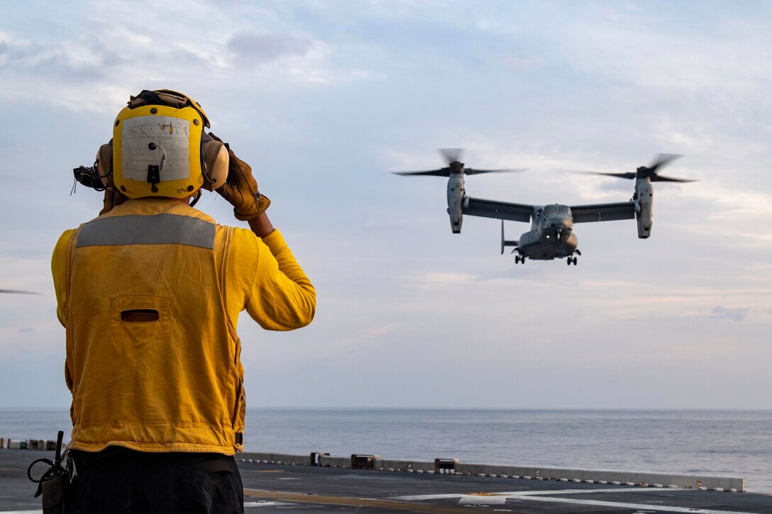 A sailor signals an aircraft.