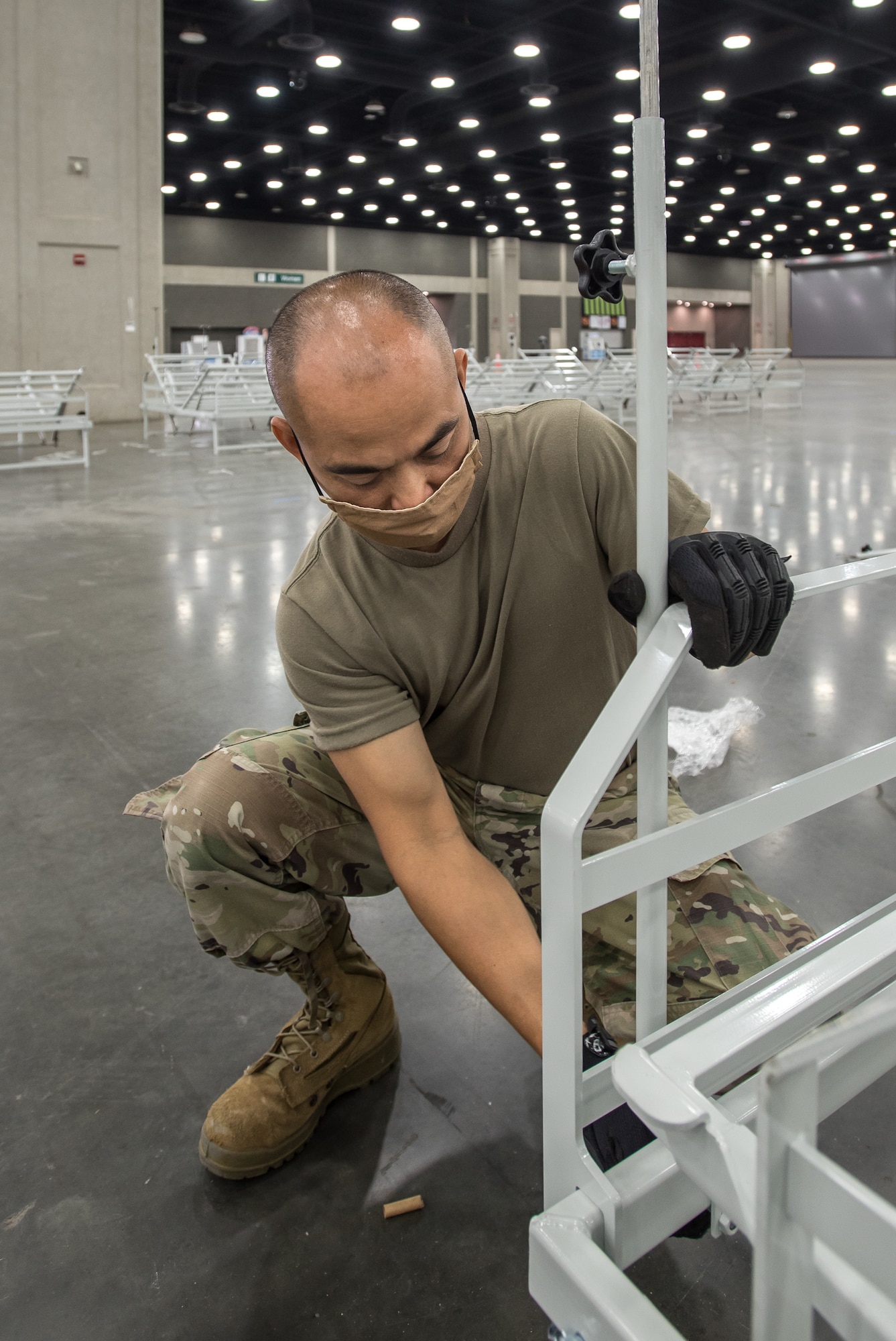 Master Sgt. Bao Huyng of the Kentucky Air National Guard’s 123rd Airlift Wing sets up hospital beds at the Kentucky Fair and Exposition Center in Louisville, Ky., April 11, 2020. The site, which is expected to be operational April 15, will serve as an Alternate Care Facility for patients suffering from COVID-19 if area hospitals exceed available capacity. The facility initially can treat up to 288 patients and is scalable to 2,000 beds. (U.S. Air National Guard photo by Dale Greer)