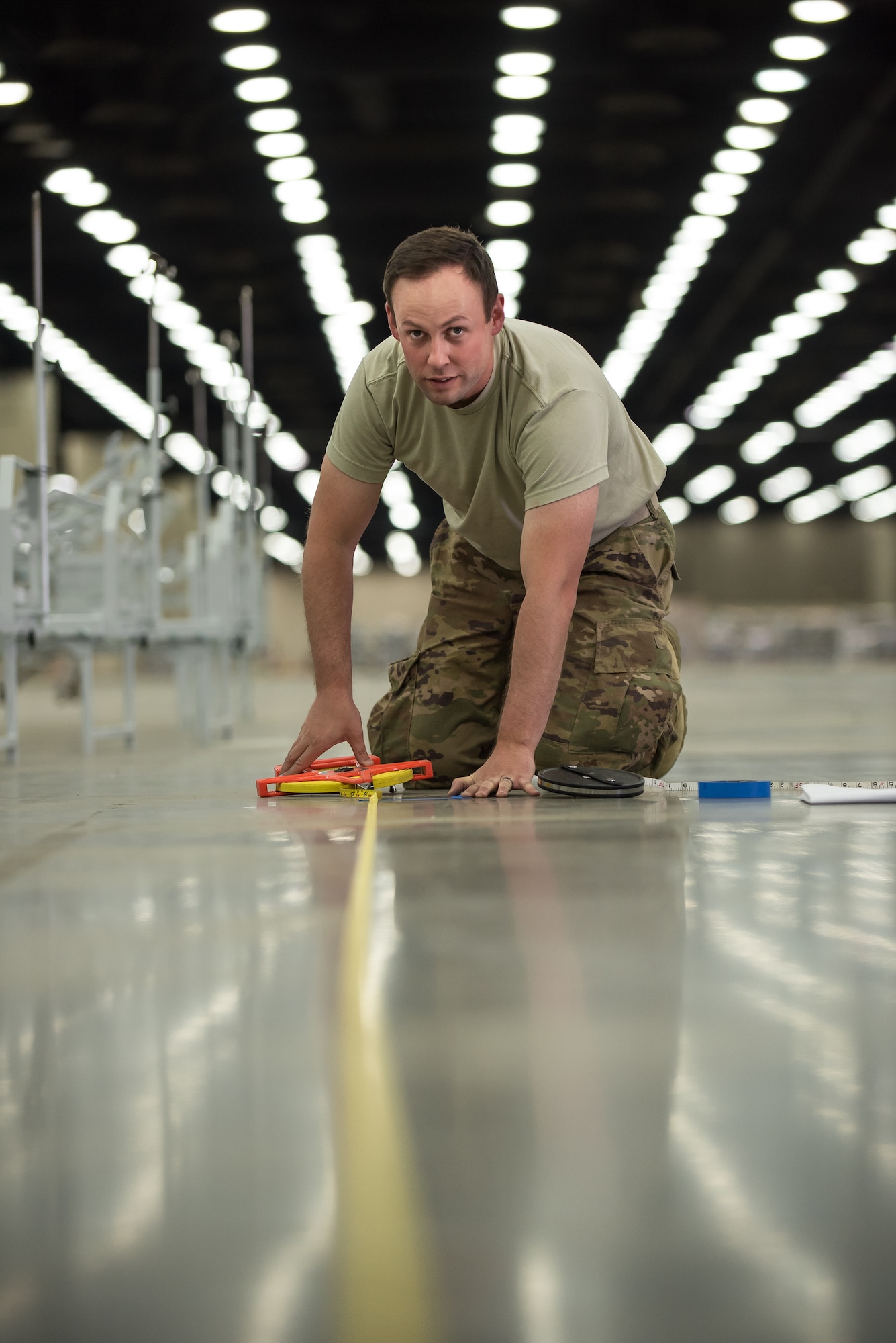 Staff Sgt. Wesley Hack of the Kentucky Air National Guard’s 123rd Civil Engineer Squadron measures floor space for hospital beds at the Kentucky Fair and Exposition Center in Louisville, Ky., April 11, 2020. The site, which is expected to be operational April 15, will serve as an Alternate Care Facility for patients suffering from COVID-19 if area hospitals exceed available capacity. The location initially can treat up to 288 patients and is scalable to 2,000 beds. (U.S. Air National Guard photo by Dale Greer)