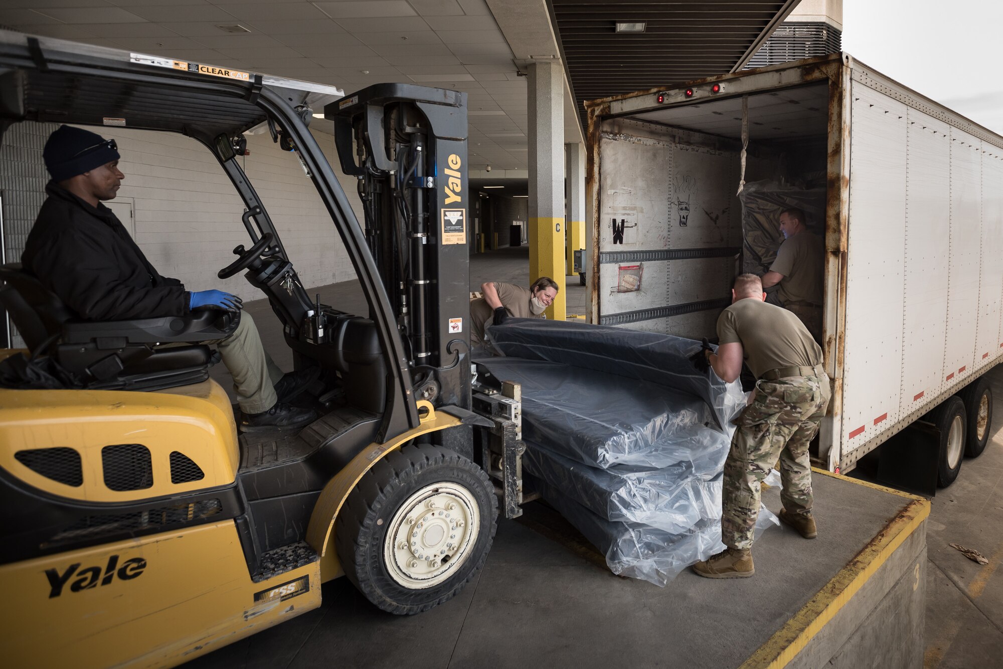 Tech. Sgt. Desiree Weingarten (center) and Tech. Sgt. Kaleb Henry (right) of the Kentucky Air National Guard’s 123rd Civil Engineer Squadron unload hospital bed mattresses at the Kentucky Fair and Exposition Center in Louisville, Ky., April 11, 2020. The site, which is expected to be operational April 15, will serve as an Alternate Care Facility for patients suffering from COVID-19 if area hospitals exceed available capacity. The location initially can treat up to 288 patients and is scalable to 2,000 beds. (U.S. Air National Guard photo by Dale Greer)