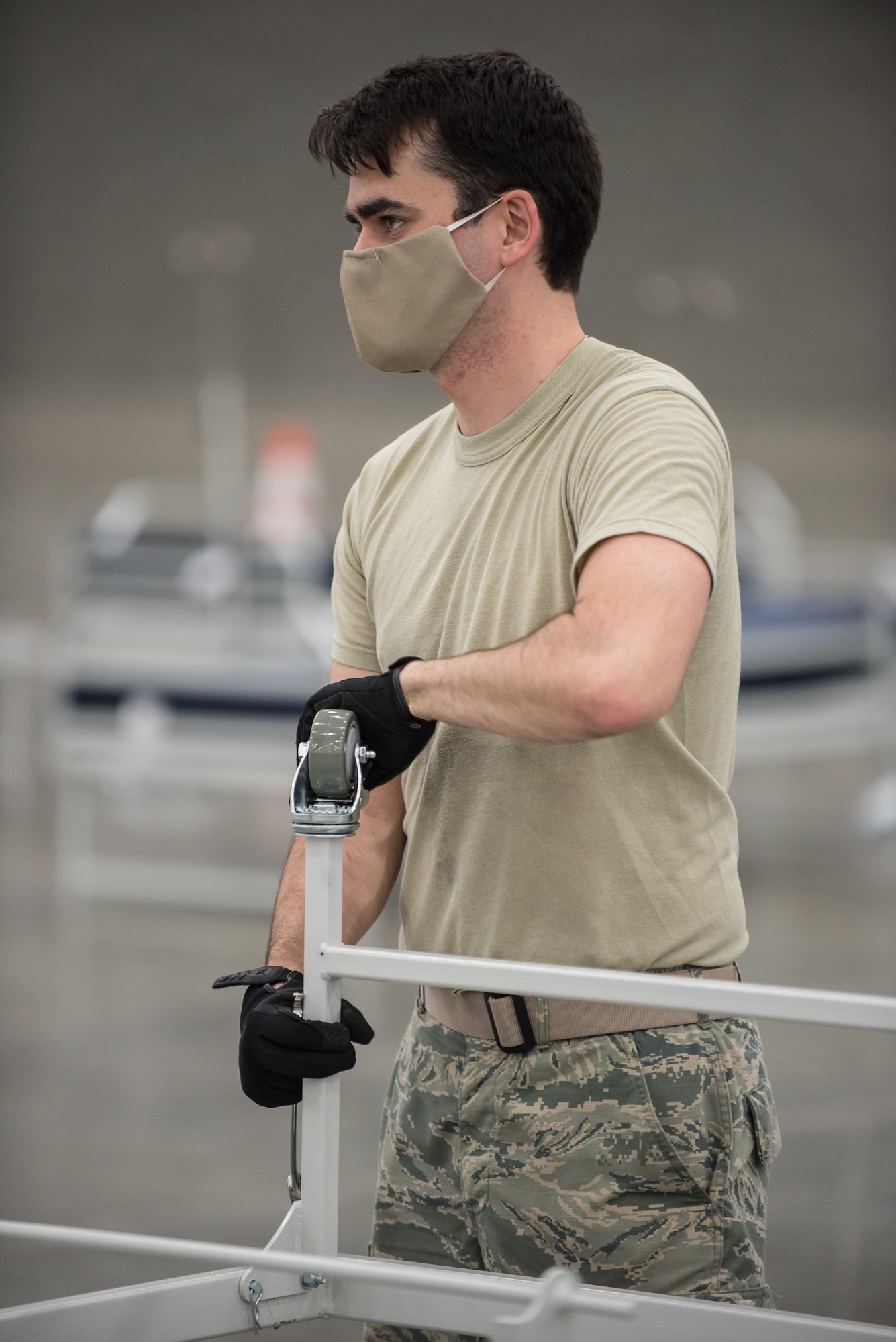 Airman 1st Class Tristan Baxter of the Kentucky Air National Guard’s 123rd Civil Engineer Squadron sets up hospital beds and clinical space at the Kentucky Fair and Exposition Center in Louisville, Ky., April 13, 2020. The site, which is expected to be operational April 15, will serve as an Alternate Care Facility for patients suffering from COVID-19 if area hospitals exceed available capacity. The location initially can treat up to 288 patients and is scalable to 2,000 beds. (U.S. Air National Guard photo by Dale Greer)