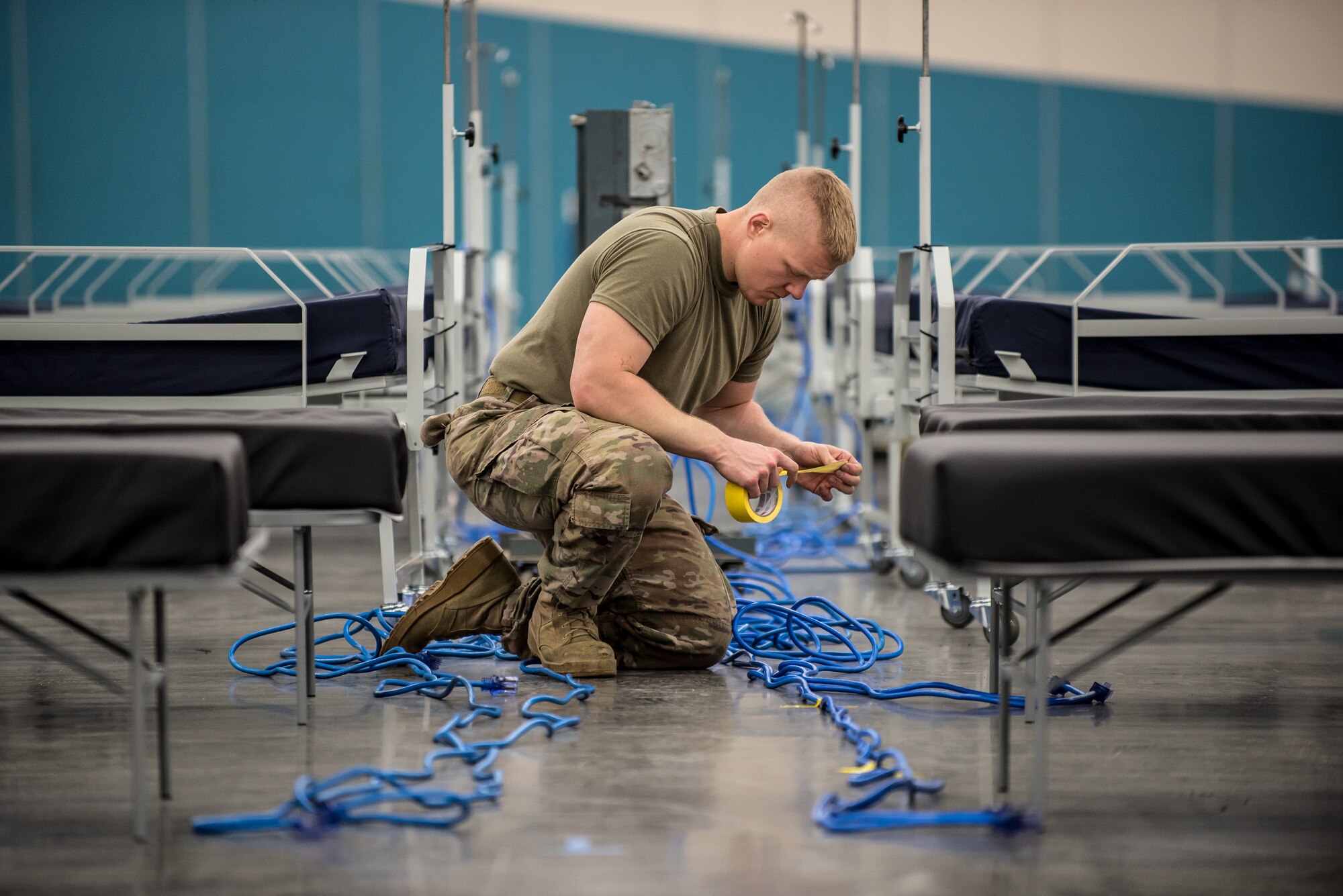 Senior Airman Samuel Wurzelbacher of the Kentucky Air National Guard’s 123rd Civil Engineer Squadron routes electrical wiring for clinical care space at the Kentucky Fair and Exposition Center in Louisville, Ky., April 13, 2020. The site, which is expected to be operational April 15, will serve as an Alternate Care Facility for patients suffering from COVID-19 if area hospitals exceed available capacity. The location initially can treat up to 288 patients and is scalable to 2,000 beds. (U.S. Air National Guard photo by Dale Greer)