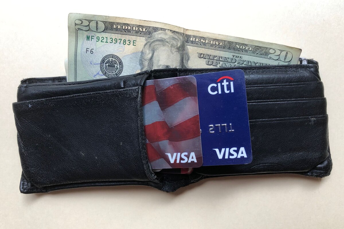 A photograph shows a wallet with money and credit cards sticking out.