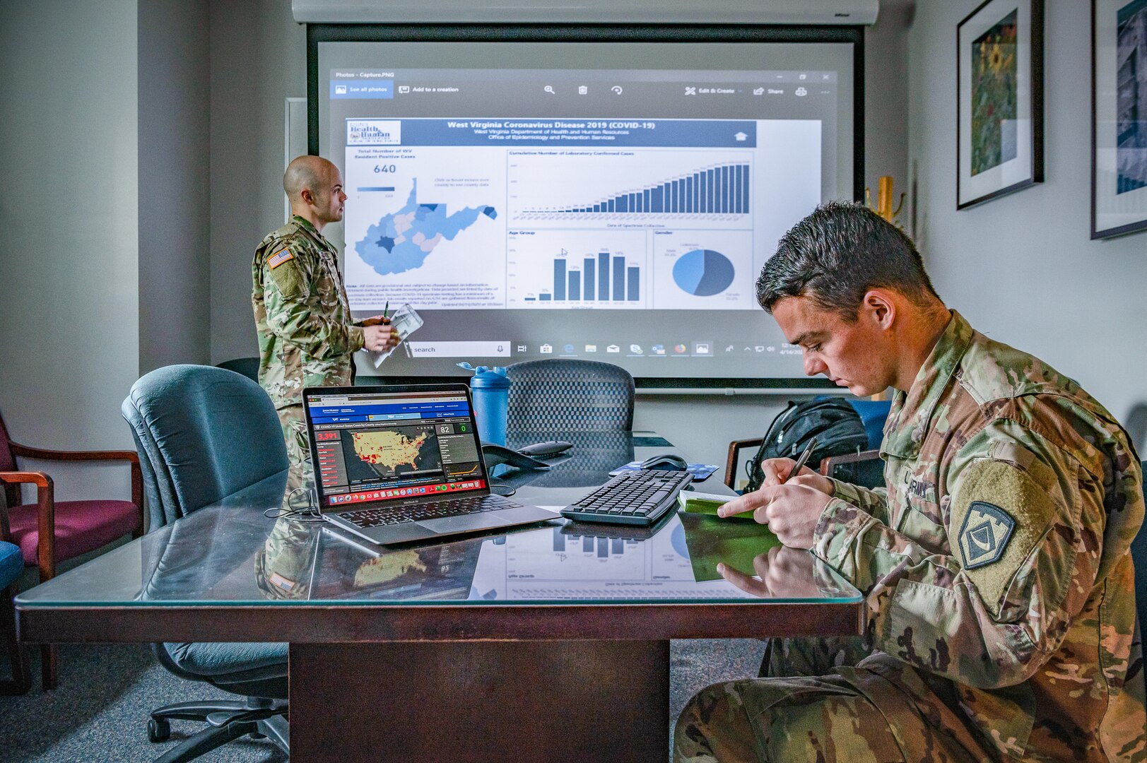 West Virginia National Guard Capt. Logan Cottrill, Intelligence Officer with the 2nd Battalion, 19th Special Forces Group (Airborne) and Warrant Officer 1 Dana Dandeneau, 772nd Aviation Troop Command, perform liaison duties with the West Virginia Department of Health and Human Resources (WVDHHR) as a part of ongoing COVID-19 response efforts in Charleston, West Virginia, April 14, 2020. The WVNG’s ability to quickly and professionally surge flexible capacity as a true force multiplier providing manpower, logistics, and to effectively apply resources across all 55 counties of the state is helping West Virginia to flatten the curve and reduce negative impacts of the pandemic. (U.S. Air National Guard photo by Staff Sgt. Caleb Vance)