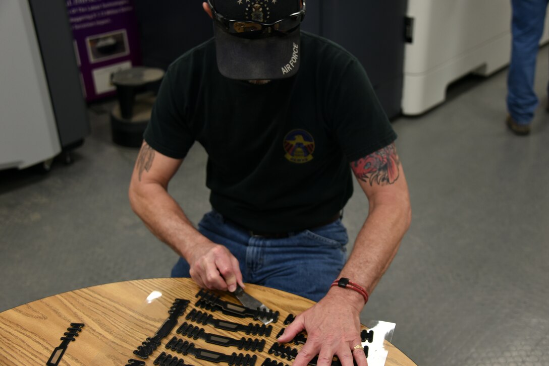 Lee Cisco, 982nd Maintenance Squadron model maker inspector, pries off freshly printed surgical mask straps at Sheppard Air Force Base, Texas, April 7, 2020. Cisco and other members of the 982nd MXS employed 3D printers already used for creating parts for the training environment and produced face shield brackets and mask straps for the fight against COVID-19. (U.S. Air Force photo by Staff Sgt. Robert L. McIlrath)