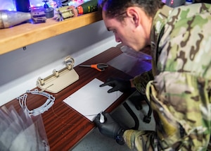 Senior Airman Jace Zook marks where to cut a piece of plastic.