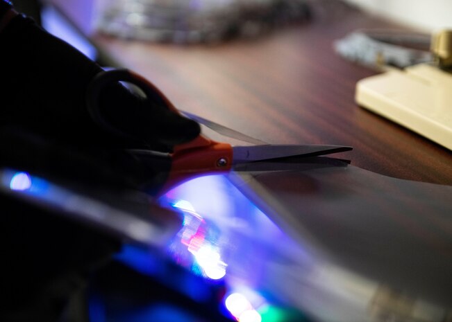 Senior Airman Jace Zook cuts a piece of plastic.