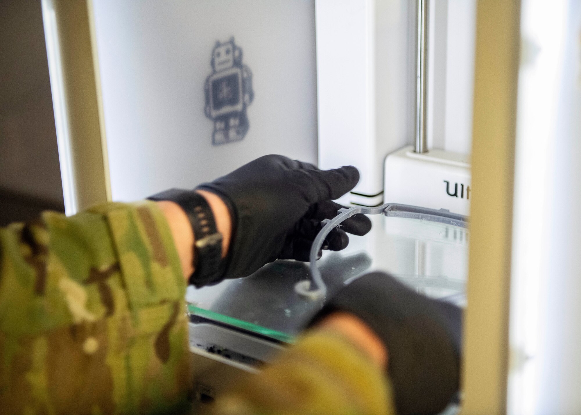 Senior Airman Jace Zook takes out a freshly printed face shield component.