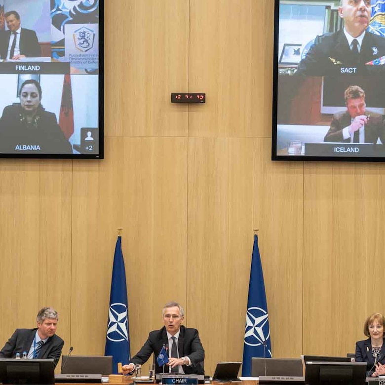 Man strikes gavel as multiple screens show remotely located participants.