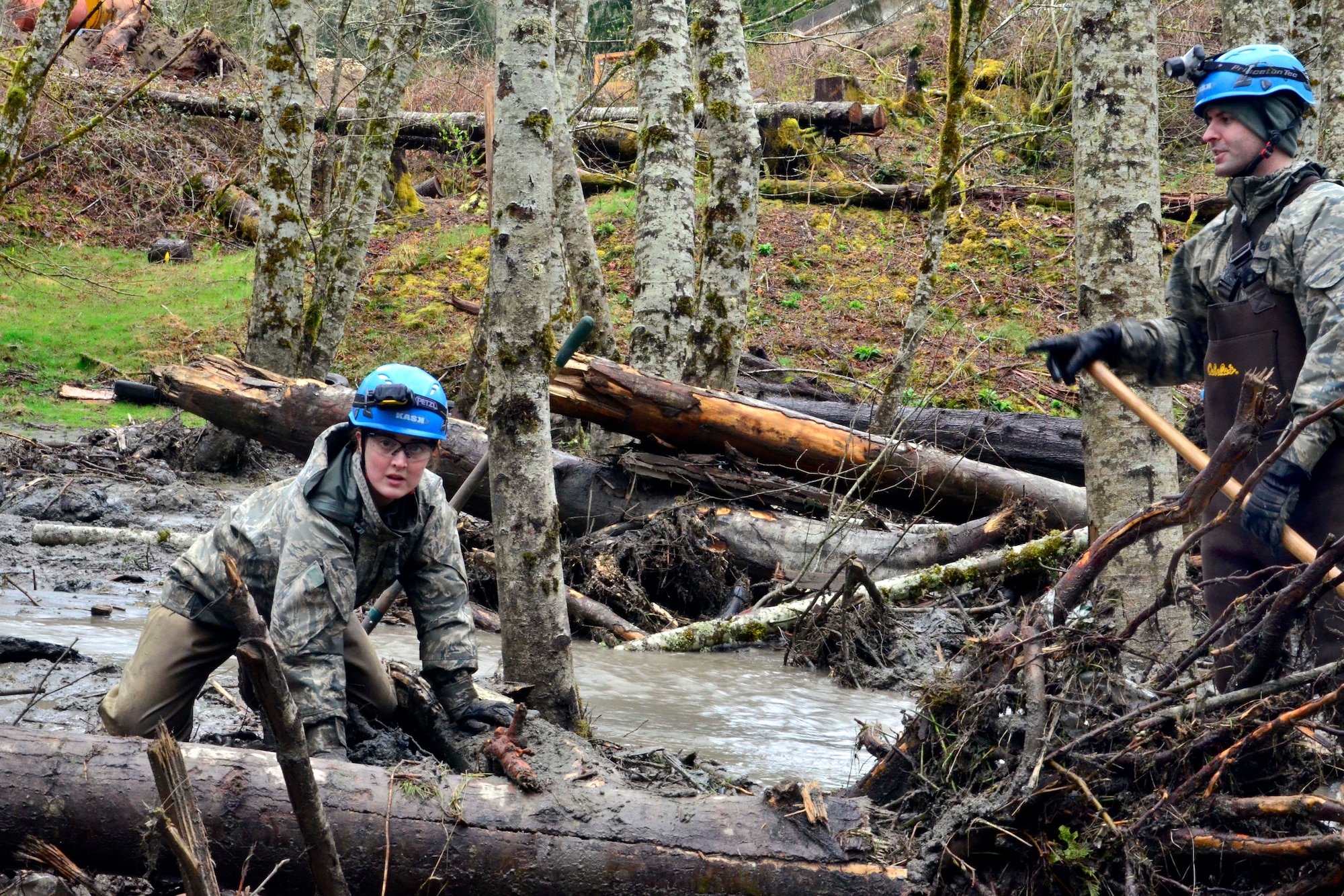 U.S. Air National Guard Capt. Nicole Stefaniak, then a Senior Airman, clears mud and debris to drain the water to assist in the search for survivors in Oso, Wash., March 30, 2014, following a deadly landslide. Stefaniak is now assigned to the Washington Air National Guard's Western Air Defense Sector and is currently volunteering for her third emergency response support to Washington state during the COVID-19 pandemic. (U.S. Army National Guard photo by Sgt. Rory Feathers)