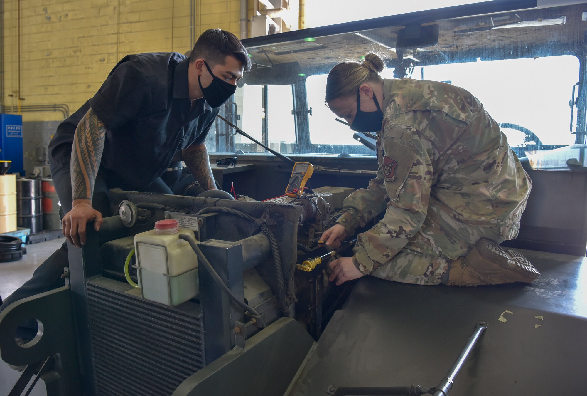 U.S. Air Force Staff Sgt. Briana Brown, 8th Logistics Readiness Squadron vehicle maintenance NCO in charge, instructs Senior Airman Micah Brady, 8th LRS vehicle maintenance  journeyman, on how to check battery voltage at Kunsan Air Base, Republic of Korea, April 14, 2020. The maintenance flight is tasked with keeping 88 different types of vehicles operational in order to meet the base’s mission demands. (U.S. Air Force photo by Tech. Sgt. Joshua Arends)