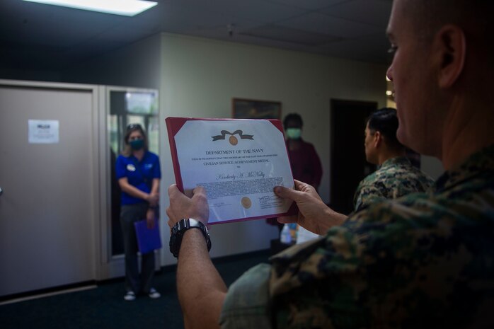 U.S. Marine Corps Sgt. Maj. Charles Wells, sergeant major, Marine Corps Base Hawaii, reads the citation of Kimberly McNally's Civilian Service Achivement Award for impactful achievement while serving as a community health nurse, MCBH, Apr. 15, 2020. Over the past sixty days, McNally consistently performed her demanding duties in an exemplary and highly professional manner in accomplishing the mission as a community health nurse during the COVID-19 outbreak. (U.S. Marine Corps photo by Cpl. Matthew Kirk)
