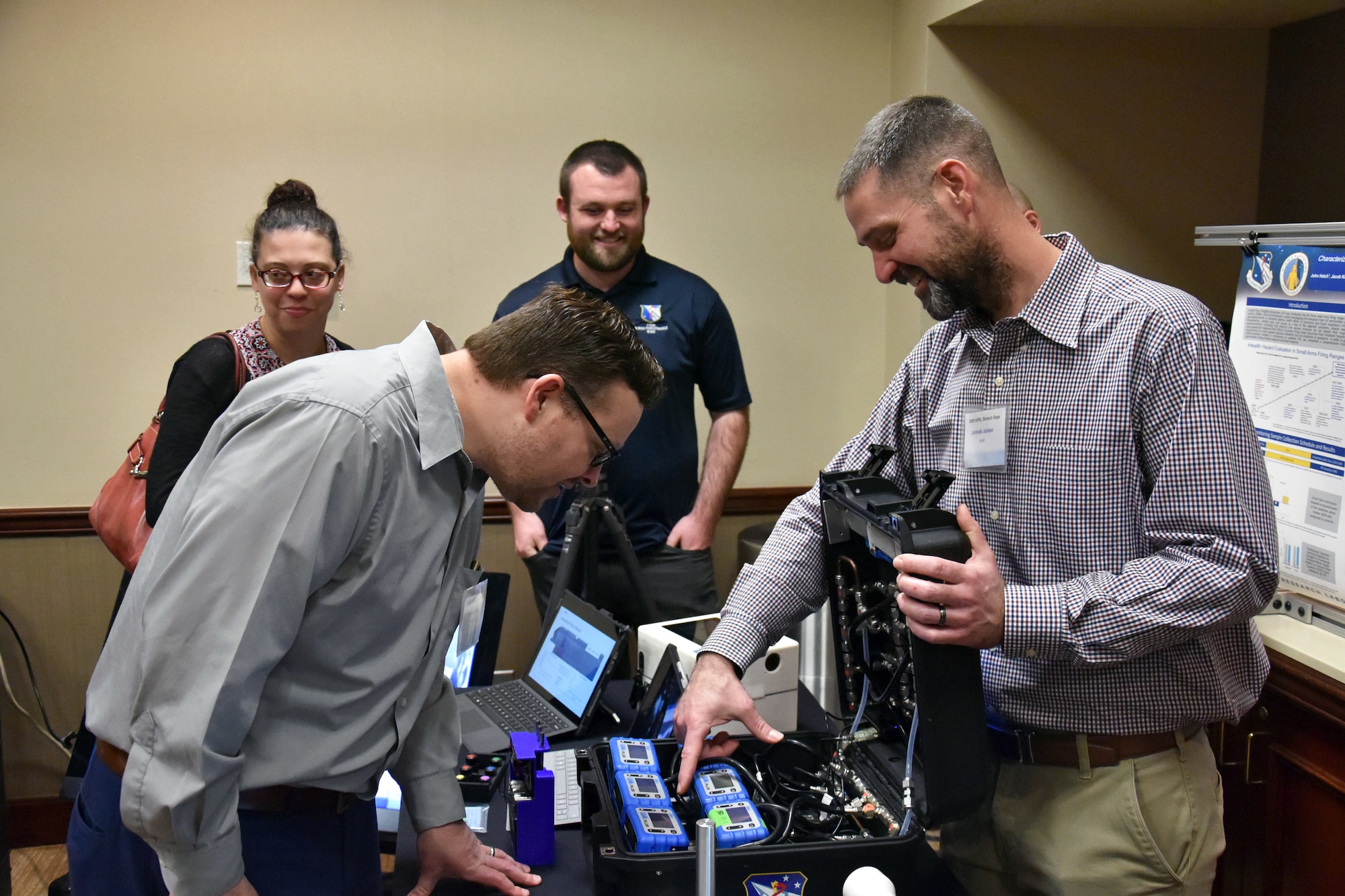 Dr. Rhett Martineau, UES/Materials and Manufacturing Directorate, visits the Environmental Assessment team demo described by Jerimiah Jackson, UES/711th Human Performance Wing. Dr. Amy Breedon and Jacke Kirsch, UES/711th Human Performance Wing, observe. (U.S. Air Force photo/Spencer Deer)