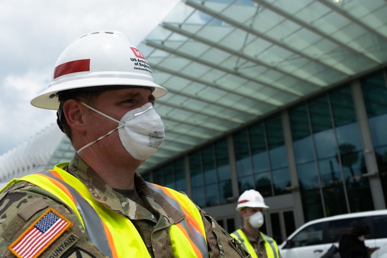 U.S. Army Corps of Engineers, Jacksonville, District deputy commander and senior project manager for the COVID-19 emergency response, Lt. Col. Todd Polk watches as leadership from the City of Miami Beach, the State of Florida and the Chief Engineer of the U.S. Army Corps of Engineers Lt. Gen. Todd Semonite brief the press and the people of South Florida on the current outlook of the COVID-19 Pandemic and the work being done at the Miami Beach Convention Center to convert it to an alternate care facility. USACE staff awarded a construction contract Monday for $22.5 Million to Robins & Morton of Miami, Fla. to convert the Miami Beach Convention Center into a 450-bed hospital. During emergencies, USACE is the federal government's lead public works and engineering support agency. Given its extensive work in building medical facilities for its military stakeholders, it is uniquely qualified to tackle this engineering challenge.