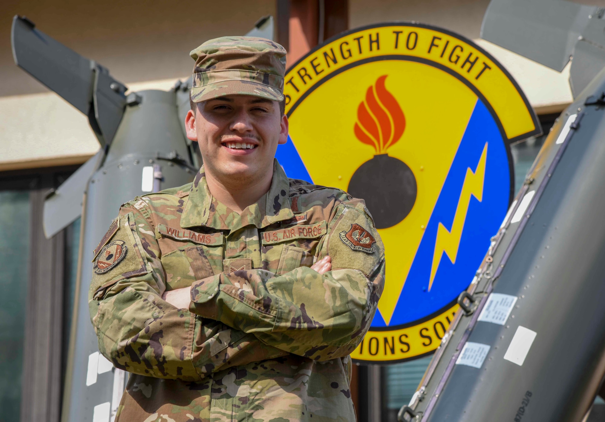 Airman poses for photo in front of squadron sign.