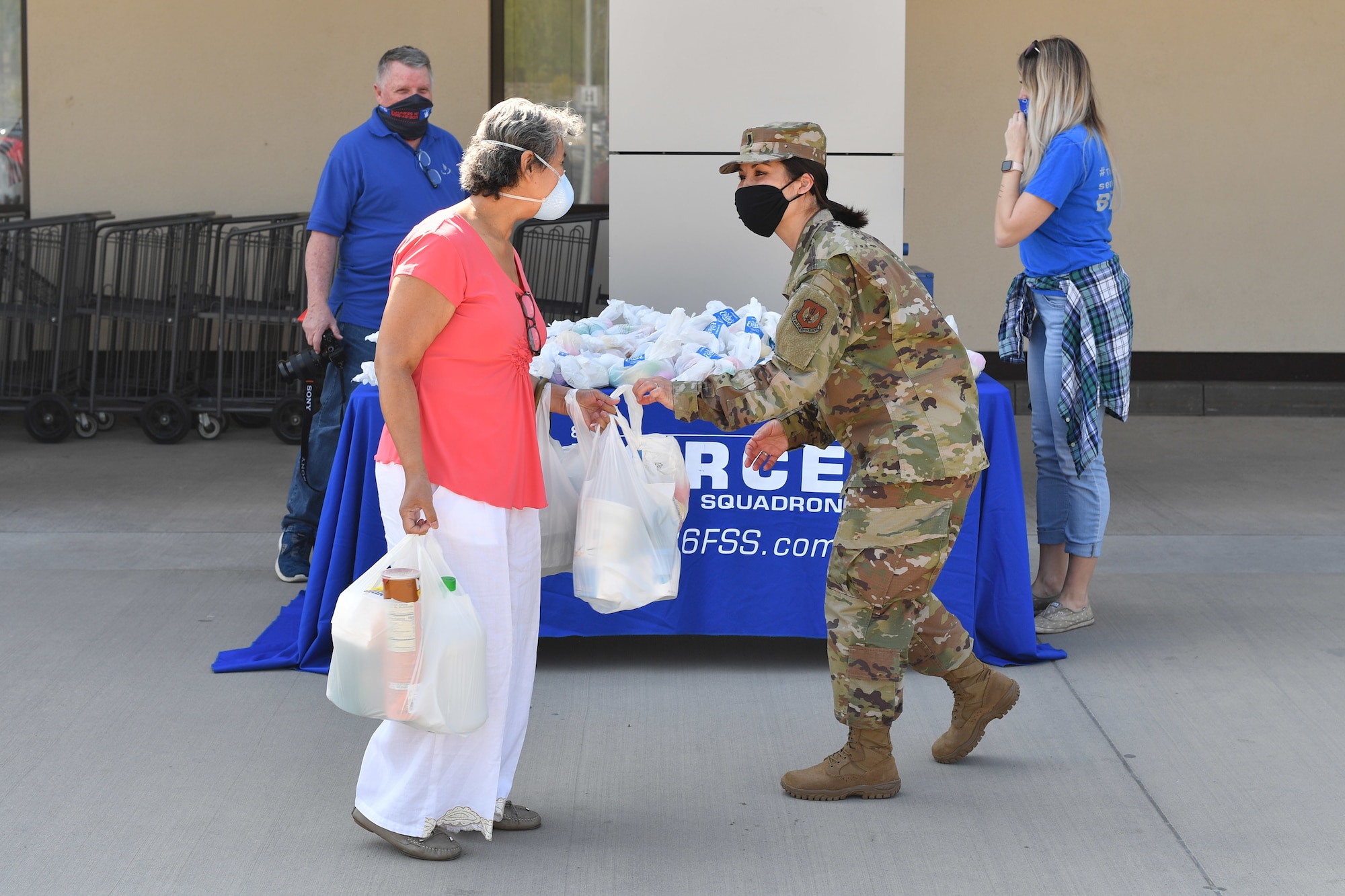 An Airman hands an Easter bag to an individual outside of the commissary.
