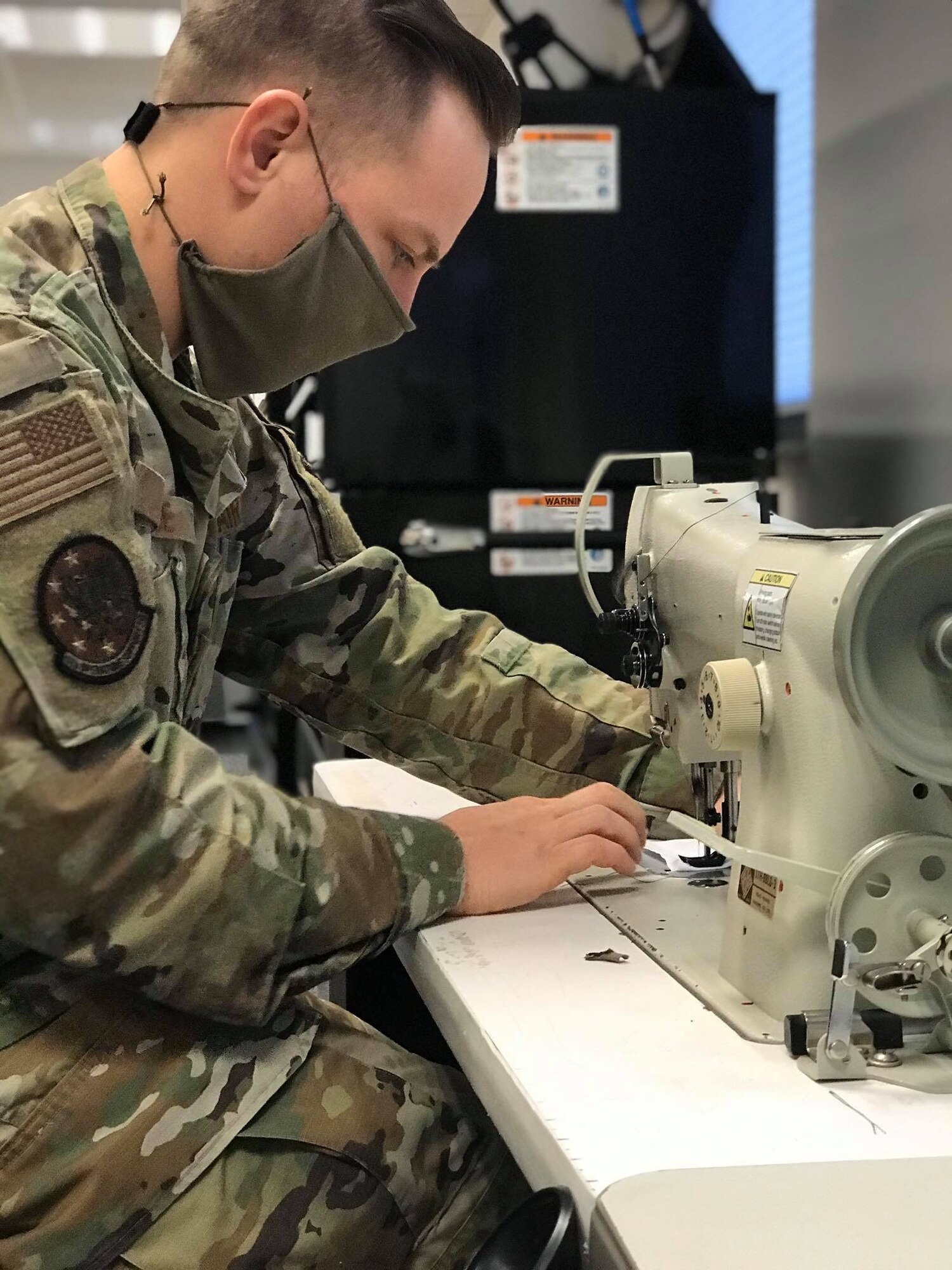 U.S. Air Force Staff Sgt. Jacob Wade, 52nd Operations Support Squadron NCOIC of aircrew flight equipment main shop, uses a sewing machine at Spangdahlem Air Base, Germany, April 13, 2020. Wade says “Providing relief to those who may not otherwise receive it is important to him during these uncertain times, and this was a great opportunity to strengthen the bond with the host nation community.” The 52nd Fighter Wing is doing everything possible to help minimize the spread of COVID-19 and is committed to limiting the spread in both the on and off-base community. (52nd Operations Support Squadron courtesy photo)