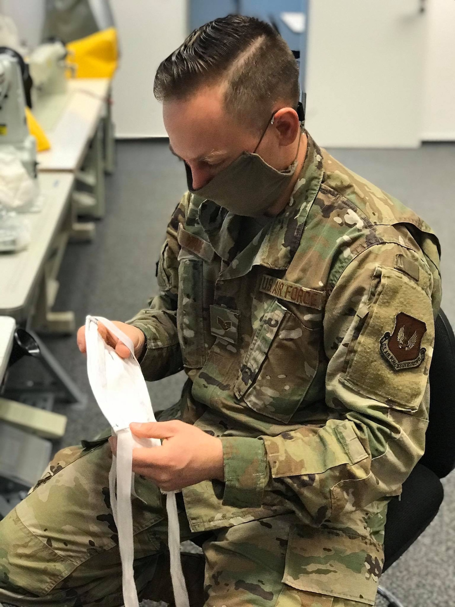 U.S. Air Force Staff Sgt. Jacob Wade, 52nd Operations Support Squadron NCOIC of aircrew flight equipment main shop, inspects a newly made a face mask at Spangdahlem Air Base, Germany, April 13, 2020. Wade and U.S. Air Force Tech Sgt. Kevin Robinson, both 52nd OSS members, volunteered to sew face masks for the base populous and local community in support of local efforts to combat COVID-19. The 52nd Fighter Wing is doing everything possible to help minimize the spread of COVID-19 and is committed to limiting the spread in both the on and off-base community. (52nd Operations Support Squadron courtesy photo)