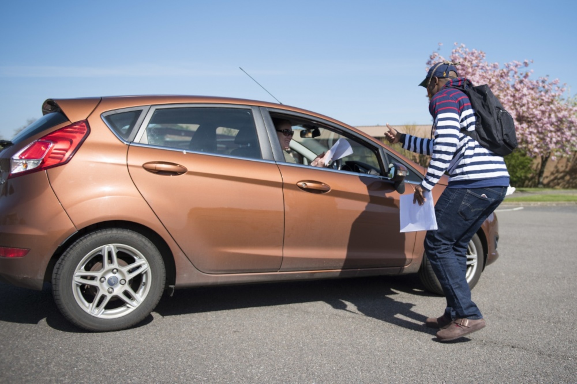 Dominique Lockley, a volunteer, hands a cloth face mask at a drive thru at RAF Alconbury, England, April 15, 2020. Volunteers made 232 cloth face masks, which were given to community members to prevent the spread of COVID-19. (U.S. Air Force photo by Airman 1st Class Jennifer Zima)