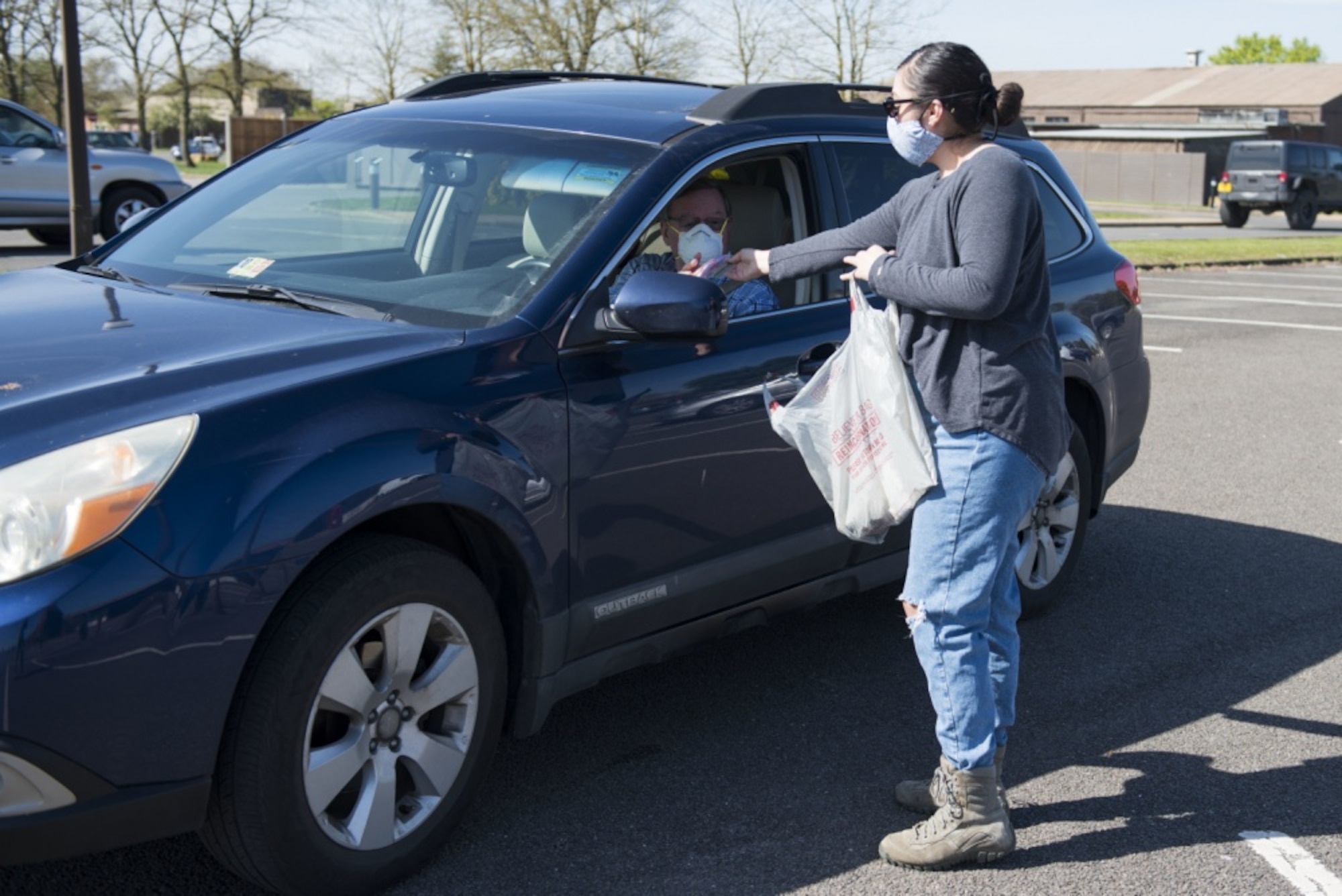 Kristin Joy, a volunteer, hands a cloth face mask at a drive thru at RAF Alconbury, England, April 15, 2020. Volunteers made 232 cloth face masks, which were given to community members to prevent the spread of COVID-19. (U.S. Air Force photo by Airman 1st Class Jennifer Zima)