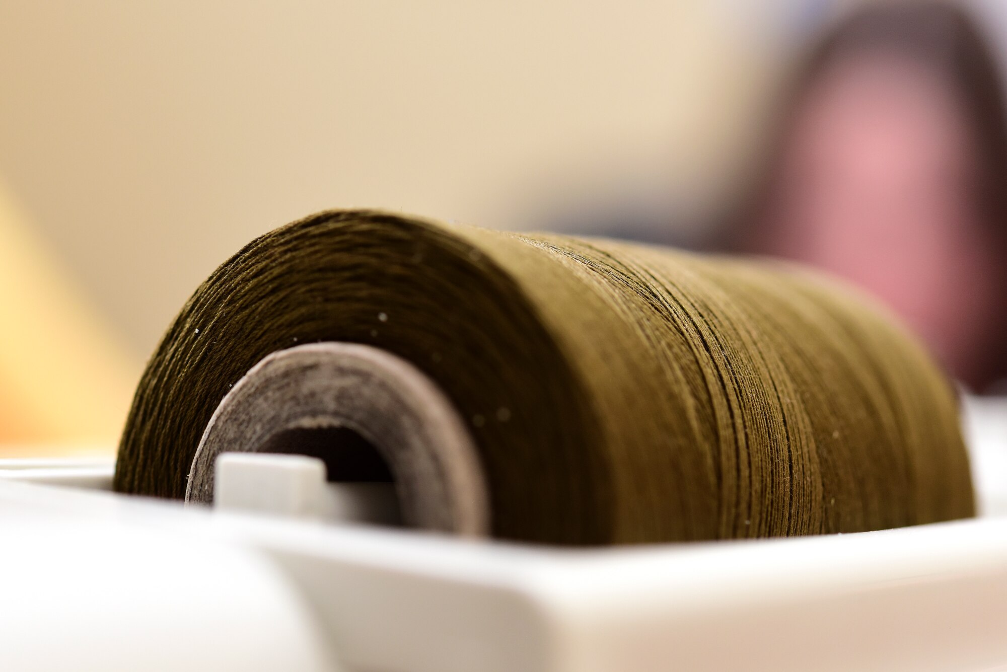 A spool of thread is loaded in a sewing machine, ready for action. XL Sew Strong is a group, primarily of spouses from Laughlin Air Force Base, Texas, who formed to sew reusable masks to help prevent the spread of COVID-19 for Airmen here. (U.S. Air Force Photo by Senior Airman Anne McCready)