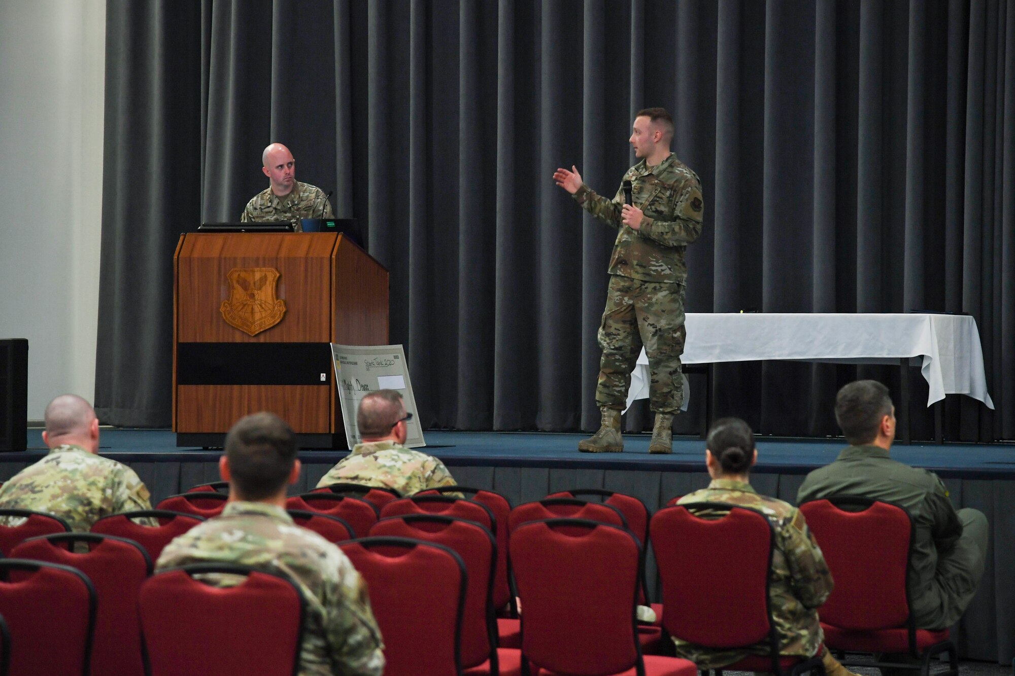 Senior Airman Daniel Kyser, 2nd Maintenance Squadron fabrication flight metals technology apprentice, presents his innovative idea in front of 2nd Bomb Wing leadership and spectators in Hoban hall during Barksdale’s Spark Tank 2020 at Barksdale Air Force Base, La., April 8, 2020. Kyser spoke on the improvements a 3D-printer would bring to not only his shop, but also to the maintenance career field. (U.S. Air Force photo by Senior Airman Taylor Hunter)