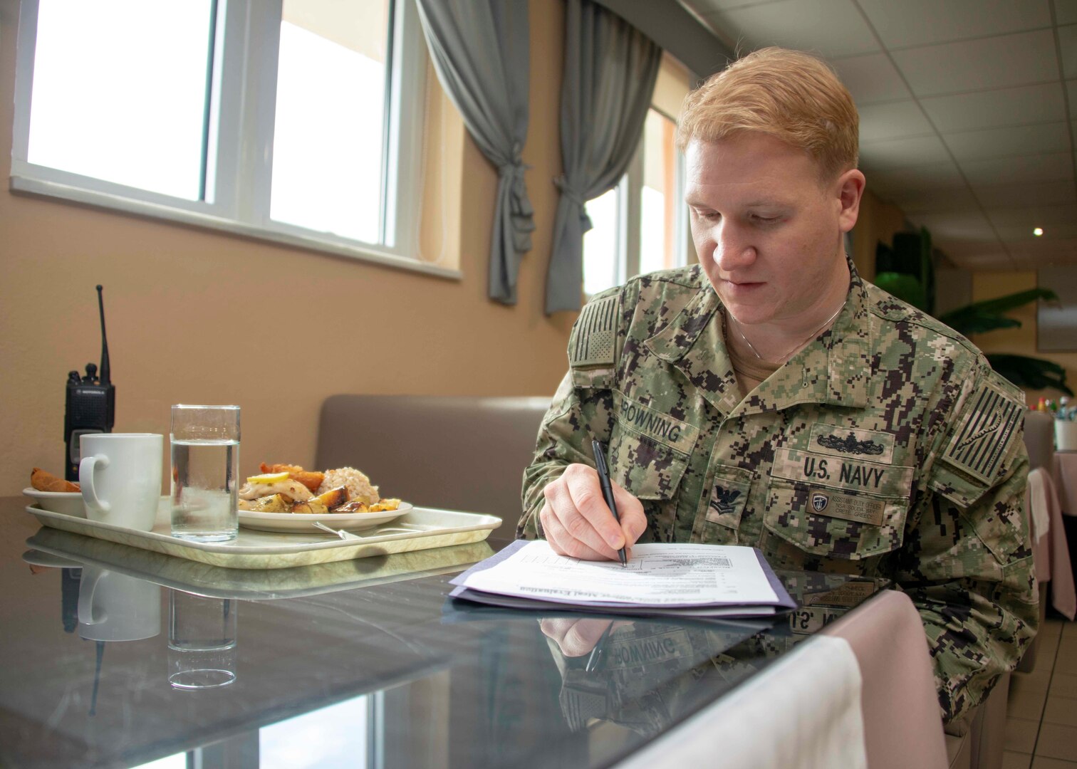 A sailor sits with a meal.