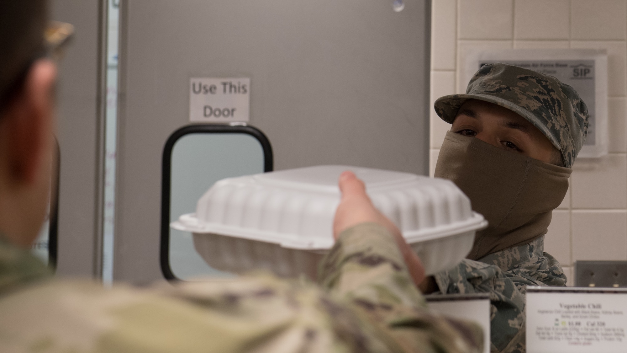 Airman Robert Rivera Sarriera, 2nd Force Support Squadron dining facility shift worker, hands a meal to a customer at Barksdale Air Force Base, La., April 15, 2020. All food items are currently being made to go. (U.S. Air Force photo by Tech. Sgt. Daniel Martinez)