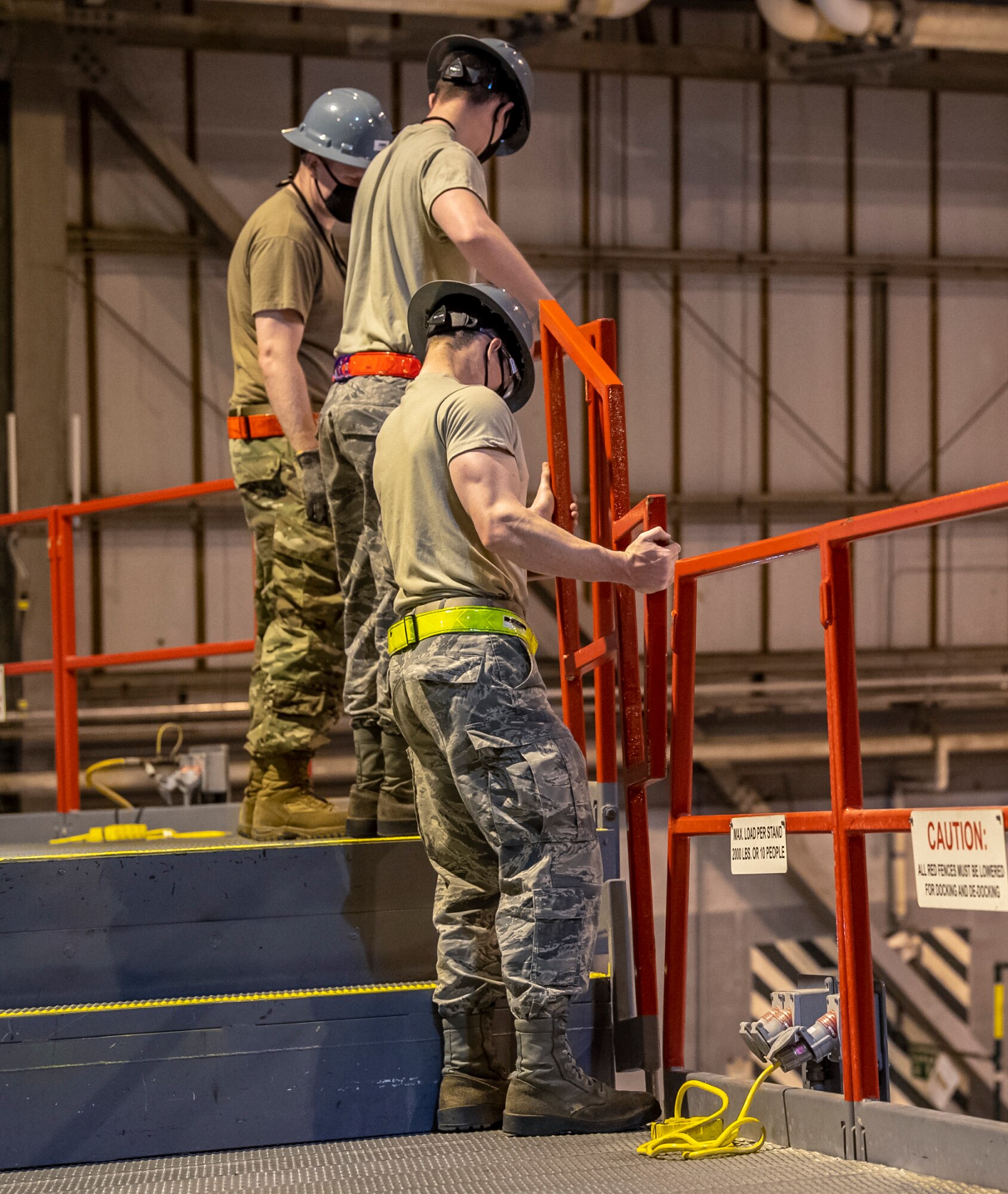 436th Maintenance Squadron aircraft maintenance personnel place guardrails along the edges of the stands in the Isochronal Inspection Dock on Dover Air Force Base, Delaware, April 9, 2020. Maintenance personnel wear cloth masks and try to maintain social distance from one another to mitigate the spread of COVID-19 while performing their duties. (U.S. Air Force photo by Senior Airman Christopher Quail)
