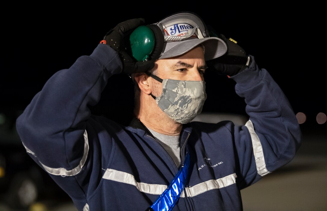 Jeff Vanderpool, 436th Maintenance Squadron marshaler, guides in a transient aircraft April 9, 2020, on Dover Air Force Base, Delaware. Vanderpool is part of the transient maintenance flight that recovers, services and launches over 1,300 non-Dover aircraft per year that transit Dover AFB. To help combat COVID-19, personnel limit direct contact with transient crews and aircraft interiors while wearing cloth masks, practicing social distancing and washing or sanitizing hands frequently. (U.S. Air Force photo by Senior Airman Christopher Quail)