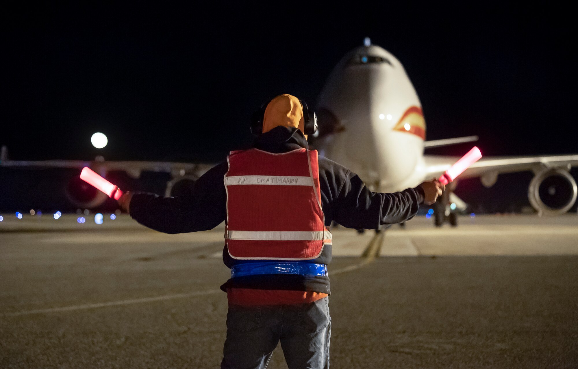 Jeff Vanderpool, 436th Maintenance Squadron marshaler, guides in a transient aircraft April 9, 2020, on Dover Air Force Base, Delaware. Vanderpool is part of the transient maintenance flight that recovers, services and launches over 1,300 non-Dover aircraft per year that transit Dover AFB. To help combat COVID-19, personnel limit direct contact with transient crews and aircraft interiors while wearing cloth masks, practicing social distancing and washing or sanitizing hands frequently. (U.S. Air Force photo by Senior Airman Christopher Quail)