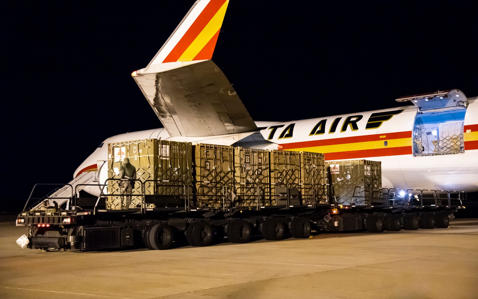 436th Aerial Port Squadron ramp services technicians unload cargo from a transient aircraft at Dover Air Force Base, Delaware, April 9, 2020. Transient aircraft teams support over 1,300 aircraft per year and continue to support those mission despite a global pandemic. To help combat COVID-19, personnel limit direct contact with transient crews and aircraft interiors while wearing cloth masks, practicing social distancing and washing or sanitizing hands frequently. (U.S. Air Force photo by Senior Airman Christopher Quail)