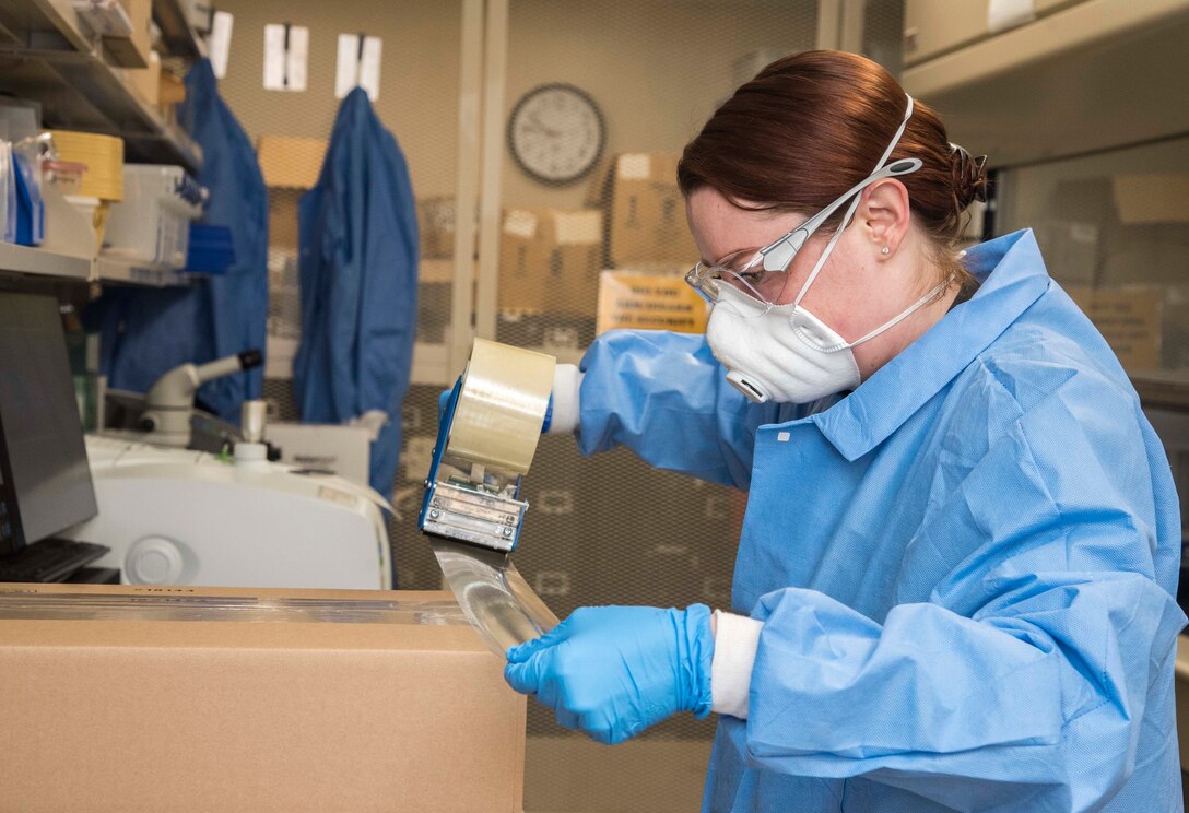 Air Force Tech. Sgt. Vivian Pimentel, Armed Forces Medical Examiner System Joint Military Working Dog Laboratory NCO in charge, creates shipping material for MWD training aids April 13, 2020. Pimentel continues to ensure the Forensic Toxicology mission continues while adhering to Centers for Disease Control and Prevention guidance to wear a face mask. (U.S. Air Force photo by Tech. Sgt. Nicole Leidholm)