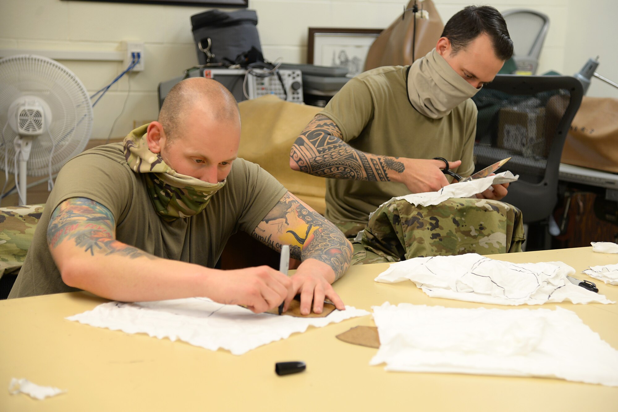 U.S. Air Force Senior Airman Michael R. Ottaviano and Staff Sgt. Brandon M. Staines, aircraft ordinance maintenance technology (Egress) technicians, volunteering to prepare fabric for face masks