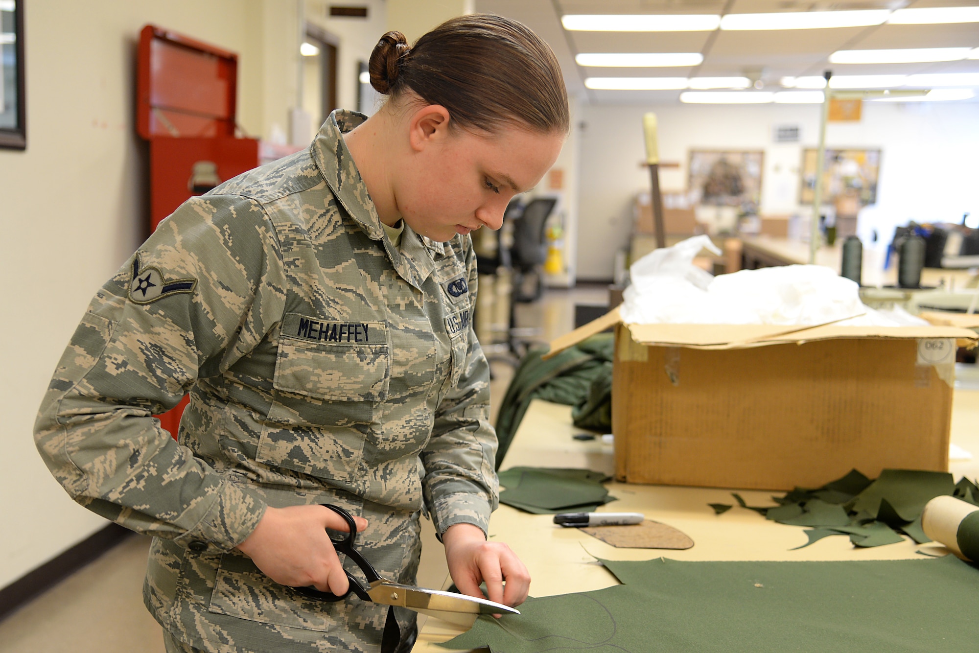A picture of U.S. Air Force Airman Makayla P. Mehaffey, an aviation resource manager, volunteering to prepare fabric for face masks