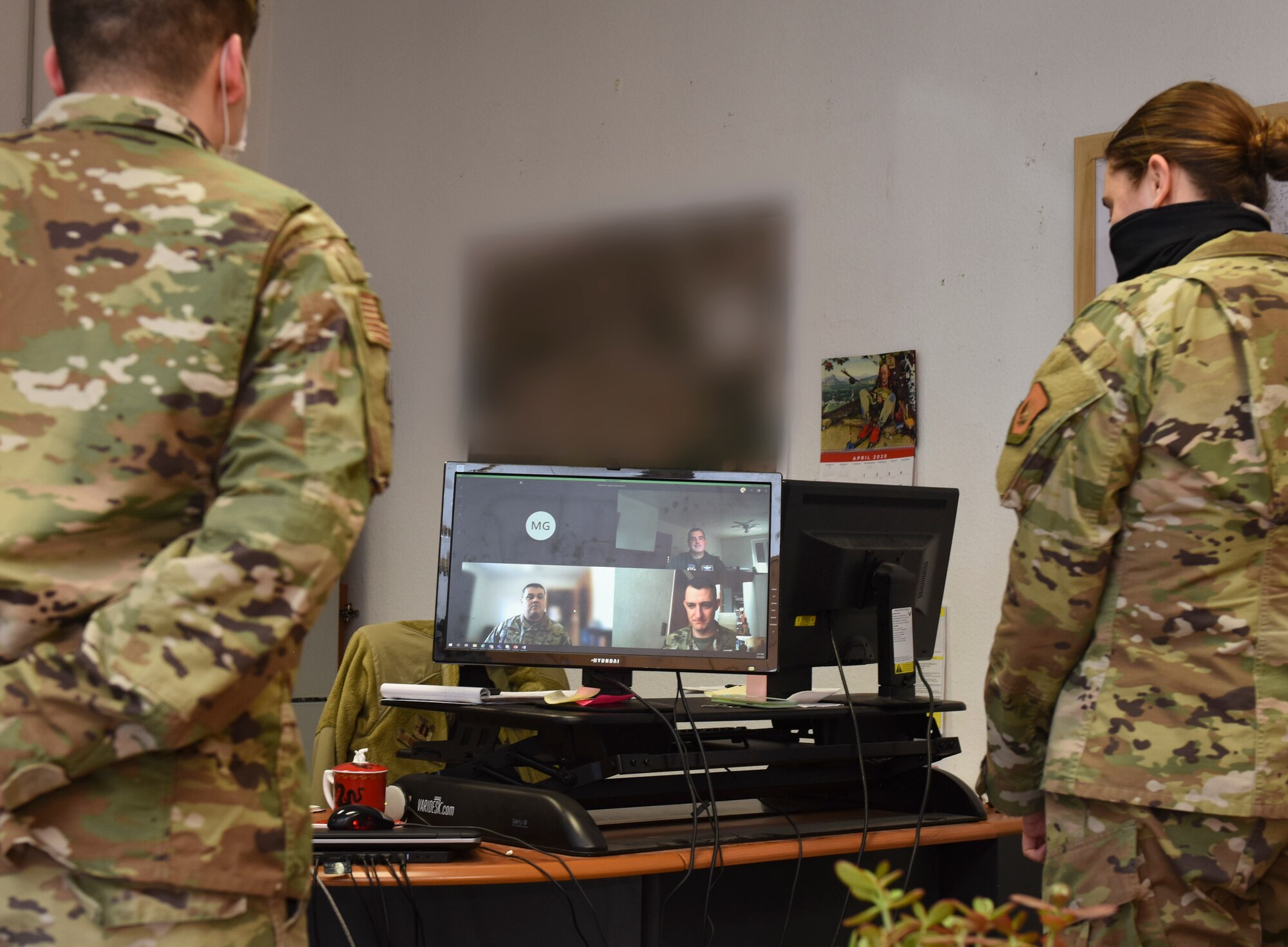 Two Airmen look at a computer monitor during a teleconference call.
