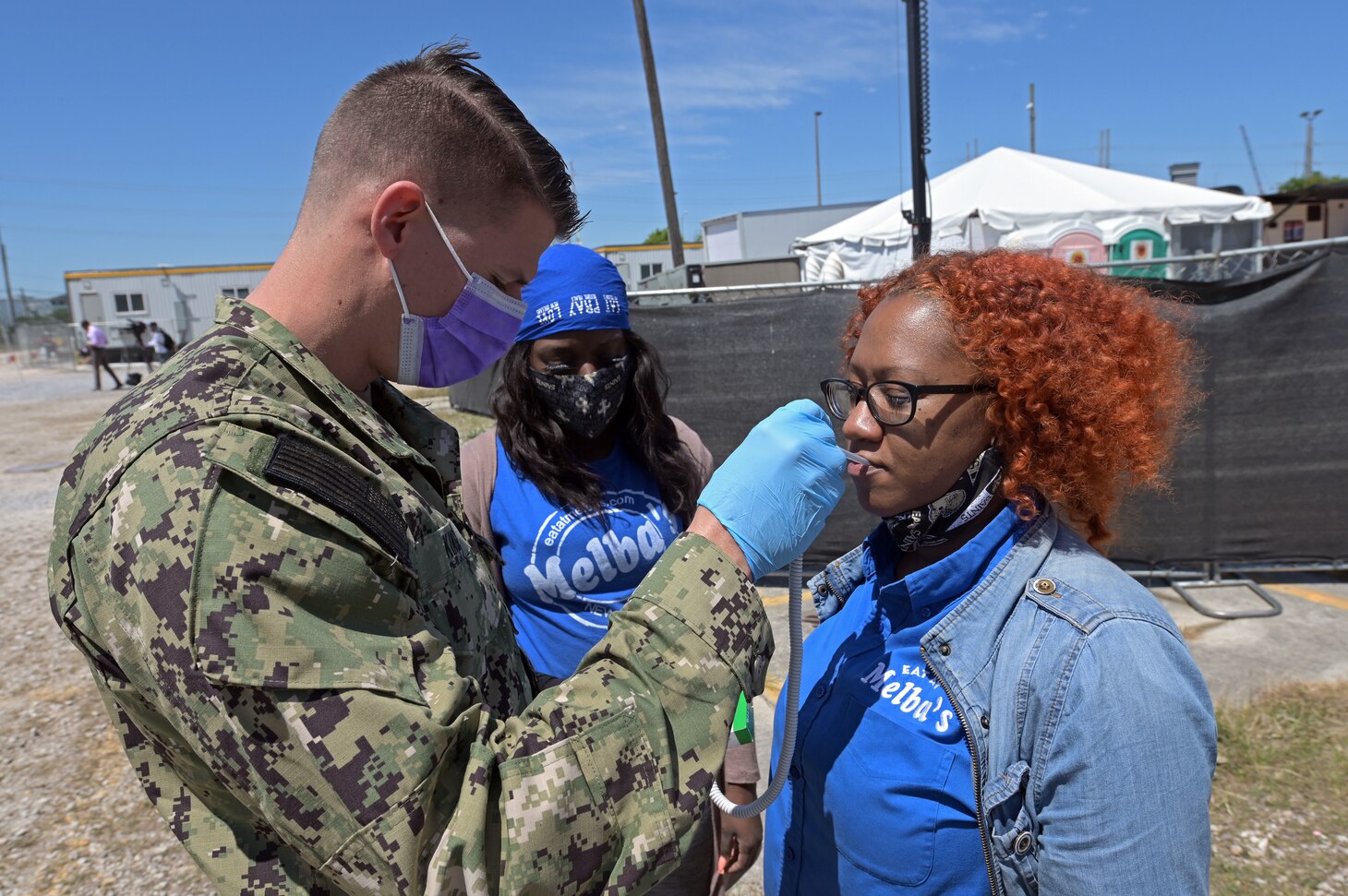 Hospital Corpsman 2nd Class Cameron King, left, with the Expeditionary Medical Facility New Orleans Detachment checks the temperature of Ralinda Guss