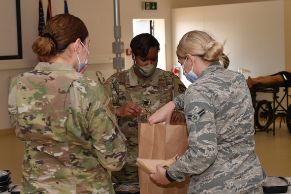 Airmen place to-go meals in a bag.
