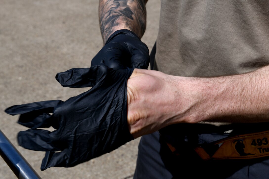 A 493rd Aircraft Maintenance Unit crew chief puts on protective gloves in preparation to sanitize an F-15C Eagle cockpit to prevent the spread of COVID-19 at Royal Air Force Lakenheath, England, April 15, 2020. Crew chiefs are required to take safety precautions to help protect themselves and other aircrew who may come in contact with the aircraft. (U.S. Air Force photo by Senior Airman Christopher S. Sparks)