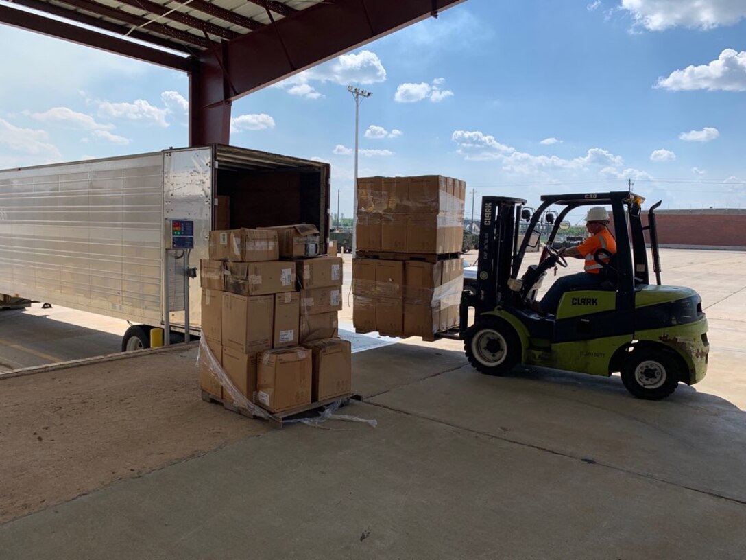 DLA Distribution employee Jason Stewart moves pallets of Tyvek protective suits onto a truck for shipment to fight against COVID-19.