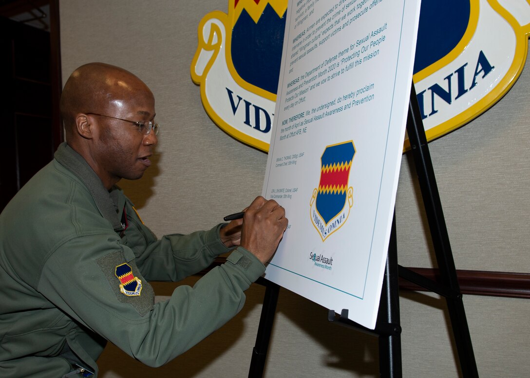 A photo of a man signing a large paper