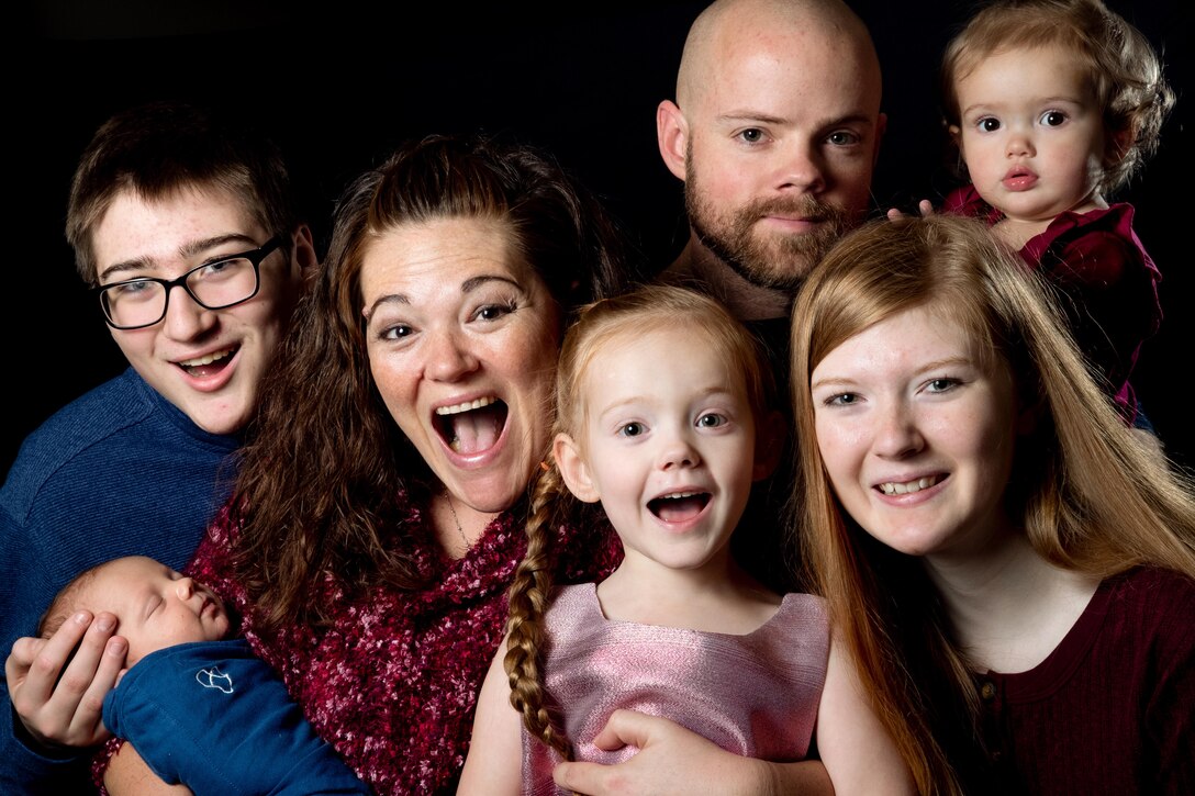 A family of seven smiles for a family portrait.