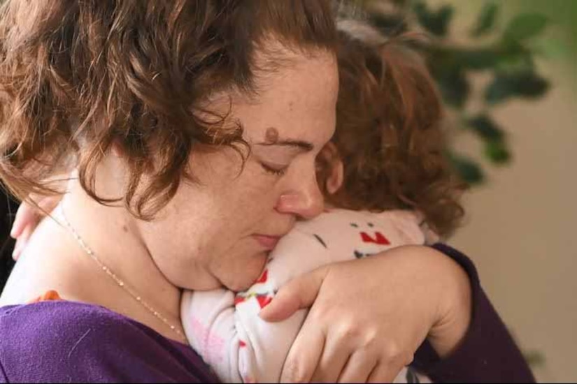 A woman hugs her 1-year-old child