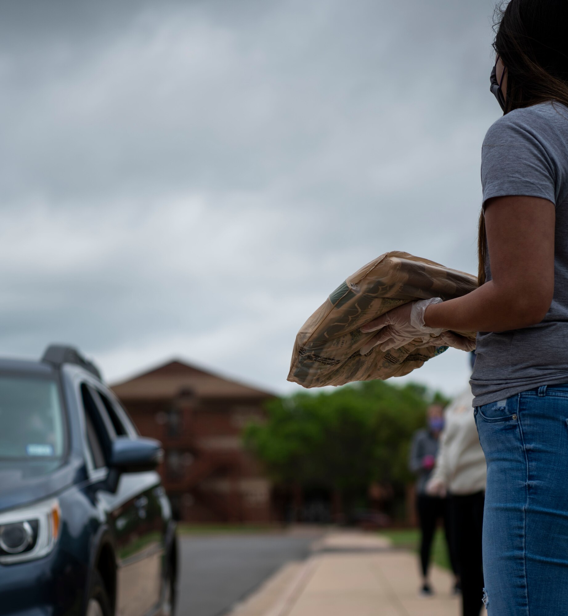 Allyson Wiseman, Dyess Spouse's Club member, distributes fabric to spouses volunteering to make face-masks at Dyess Air Force Base, Texas April 11, 2020.