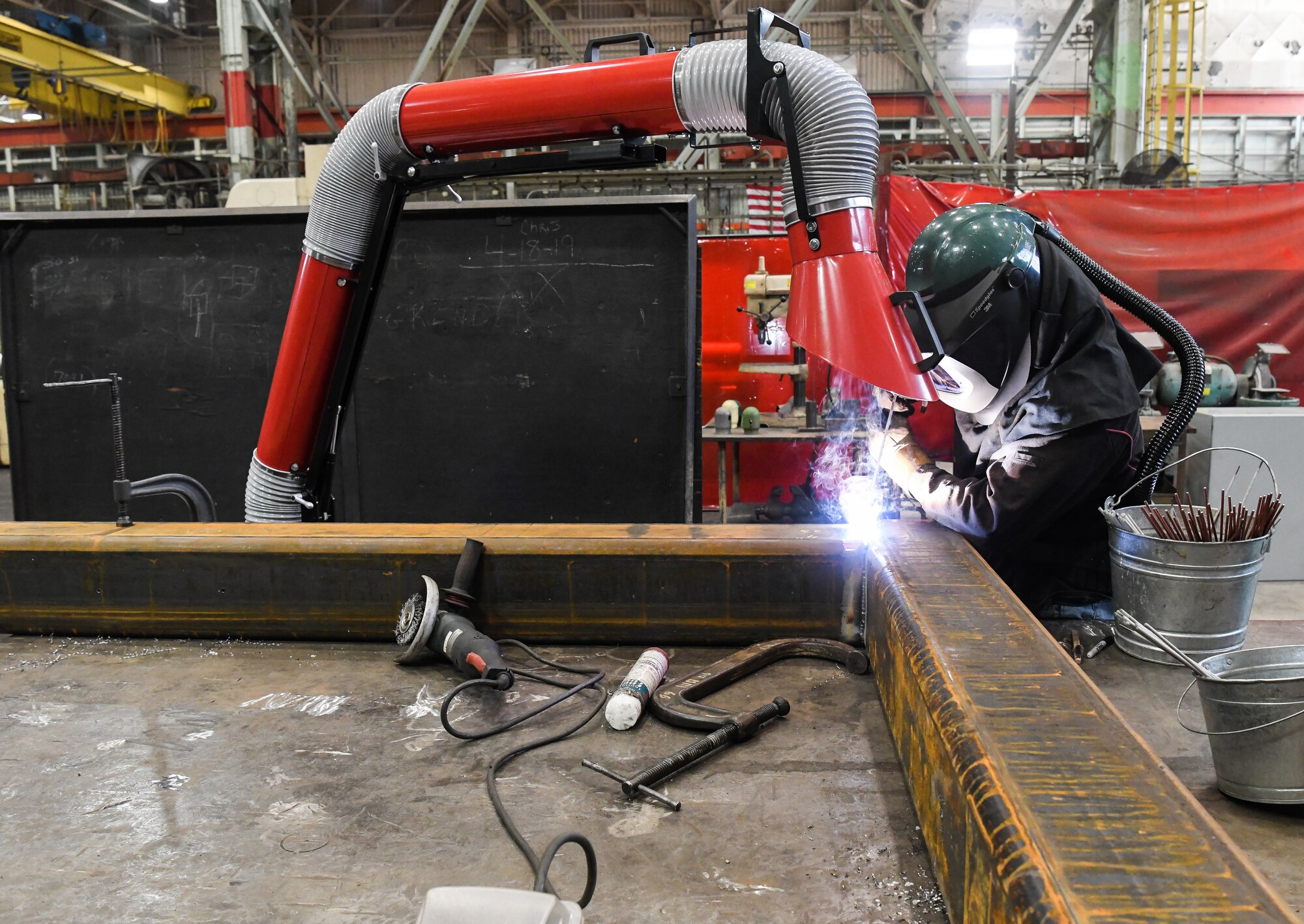 Chris Easterly, an ironworker, welds a joint on a C-1 pipe support stand April 1 in the Model and Machine
Shop at Arnold Air Force Base, Tenn. Easterly is wearing a welding helmet with a powered air purifying
respirator (PAPR) and a hood, which provides protection from smoke and fumes. The PAPR is not required
for welding non-stainless steel, but is being explored as a risk mitigation option for when craftsworkers
need to be closer than six feet apart to complete the task. (U.S. Air Force photo by Jill Pickett)